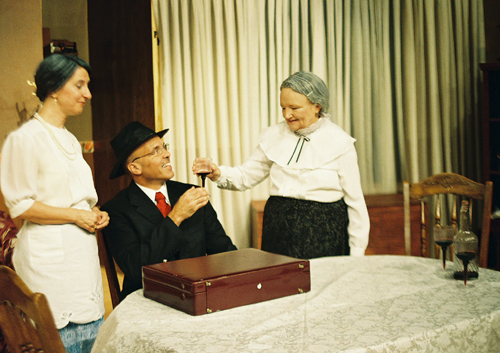 Two woman standing and one man sitting at a table