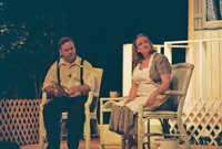 A man and a woman sitting in front of a house