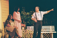 An older man pointing while two women look on