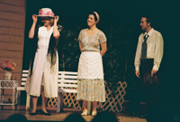 An older woman trying on a hat while a man and a woman look on