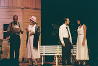 A man in glasses talks with an older woman, and a young man talks to a young woman