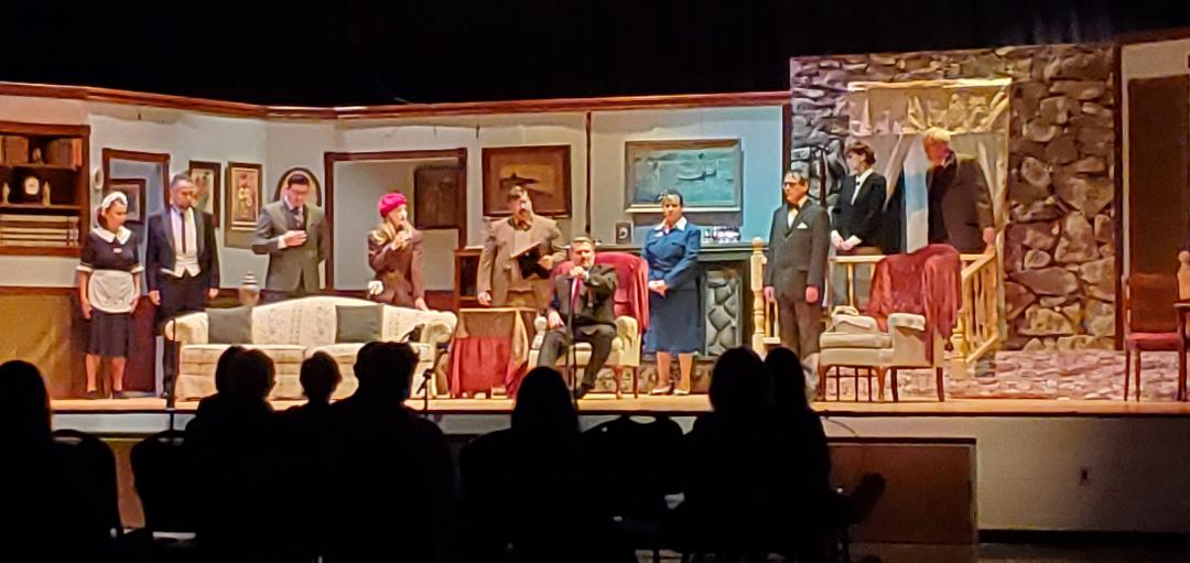 A maid, a butler, a man in a gray suit, a woman in a red cap, a man in a brown suit, a man in
       a dark gray suit sitting in a chair, a woman in a blue dress, a man in a gray suit, a woman in a black suit, and a
       man in a brown jacket