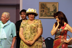 A man in a blue shirt and ascot, a minister, a woman in a floral print dress and a woman looking sad