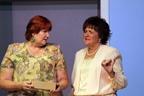 A woman in a floral print dress and a woman in a beige dress talking