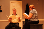 A sitting man and woman reading from scripts