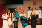 Five women, one holding a white dress, four holding an aquamarine-colored dress