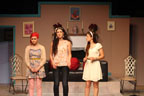 Three women talking, one with red hair, one wearing jeans, and one wearing a white dress