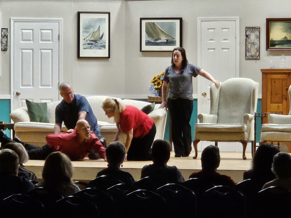 A man laying on his stomach in pain, another man and a woman kneeling to help, and another woman standing.