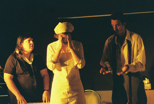 A man talking to two women, one with her head in her hands