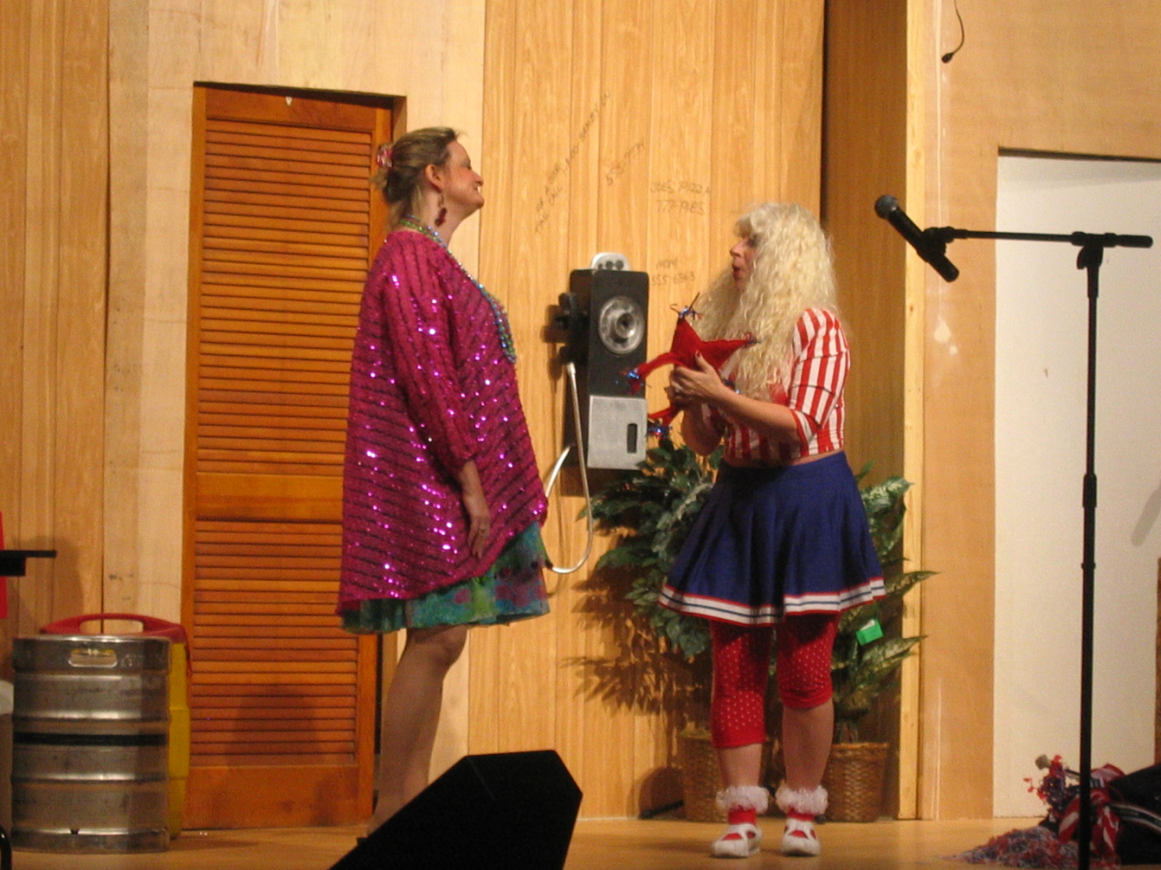 Two women standing, one in a sparkling purple coat, another in a red white and blue dress and blouse