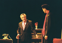 Two men talking in front of a short bookcase