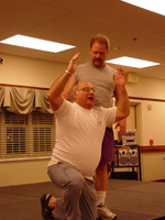 A man standing over another man on his knees