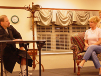 A man at a table and a woman sitting on a couch 