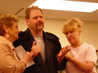 Two women on either side of a man wearing a dark coat