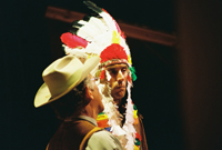 A man in a cowboy hat talking to a Native American man in a headdress
