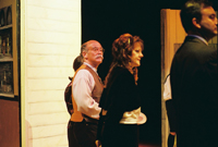 A bald man, a woman and a man in a suit standing together