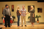 A man in a gray shirt and tie, a young woman in jeans and sandals, a young man in a plaid shirt, and a woman in a horizontally
       striped long dress