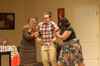 Two women hold the arms of a young man in glasses and a plaid shirt