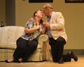 A woman on a couch about to be kissed by a man kneeling on the floor