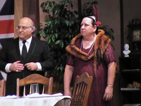 A man in a suit and a woman with a fox fur standing behind a table